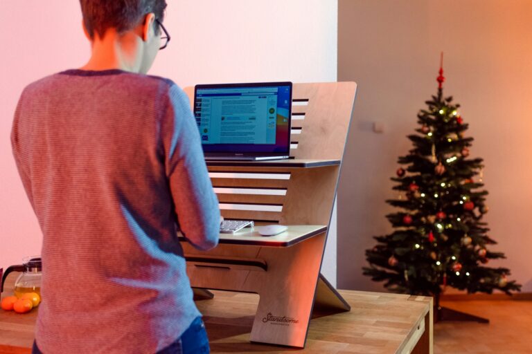 Man at a computer stand in a modern office with Christmas tree in the background